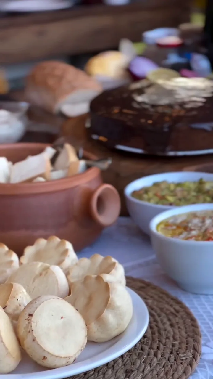 Mesa de café com pães de queijo, bolo e cremes